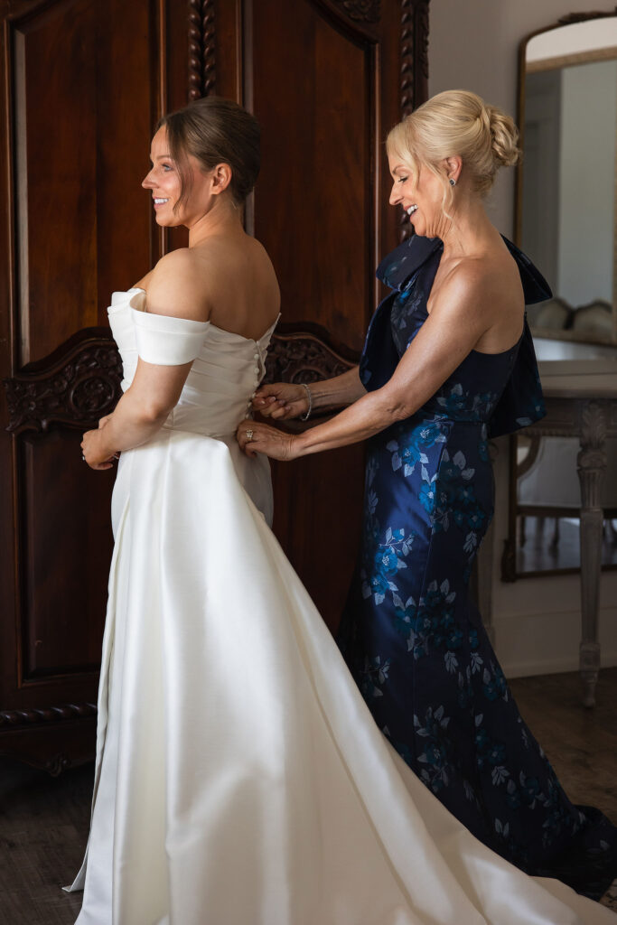 bride getting zipped into her wedding gown by mother