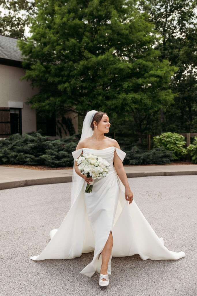 bride walks towards camera in white layered wedding gown with off shoulder detail