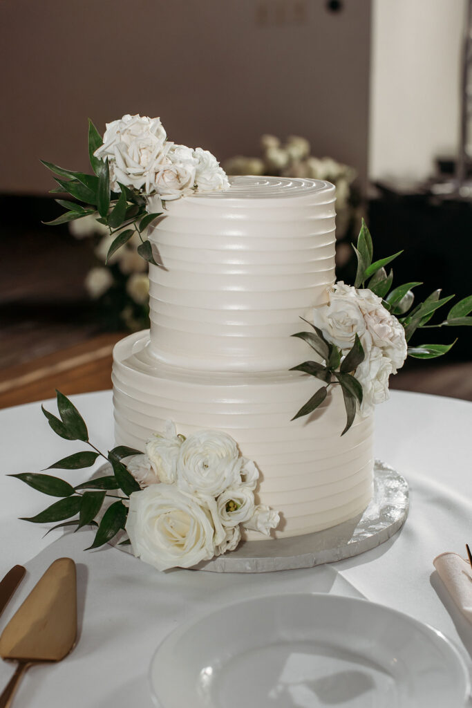 two tiered white wedding cake with all white floral decor