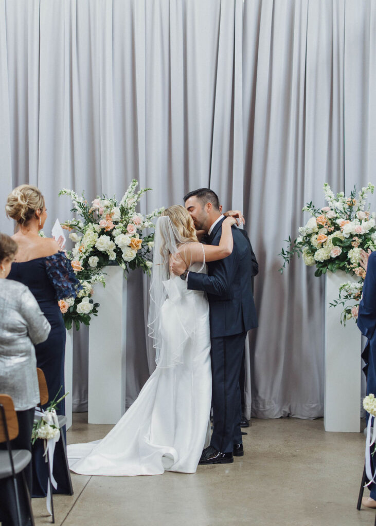 bride and groom kiss at wedding ceremony at Olive and Oak wedding