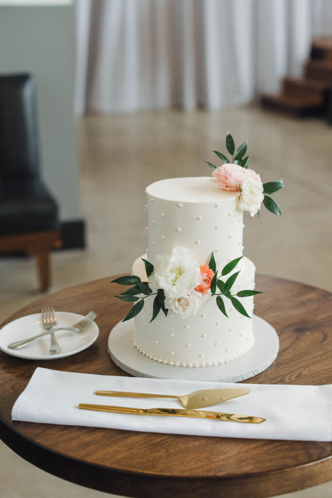 two tiered all white wedding cake with pearl dots