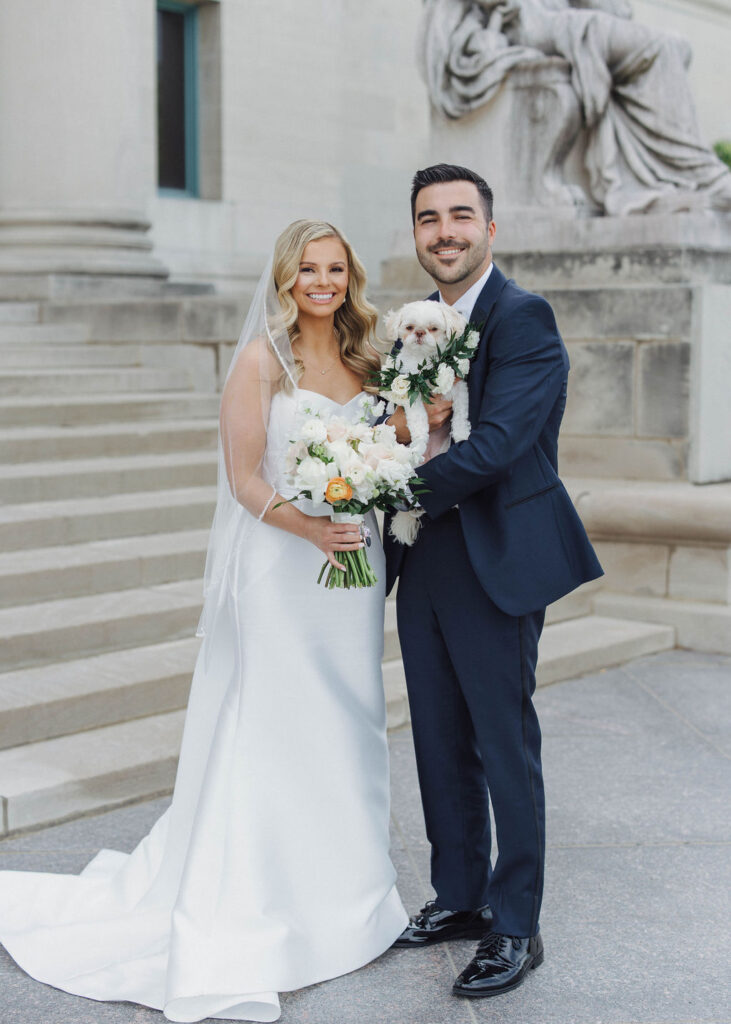 bride and groom holding white dog posed at Olive and Oak wedding